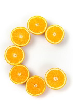 Several pieces of fresh oranges in the form of letter C. Isolated on white.